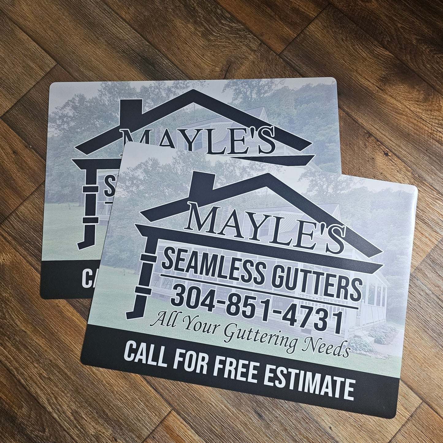 Mayle's Seamless Gutters promotional car magnet signs on a wooden background