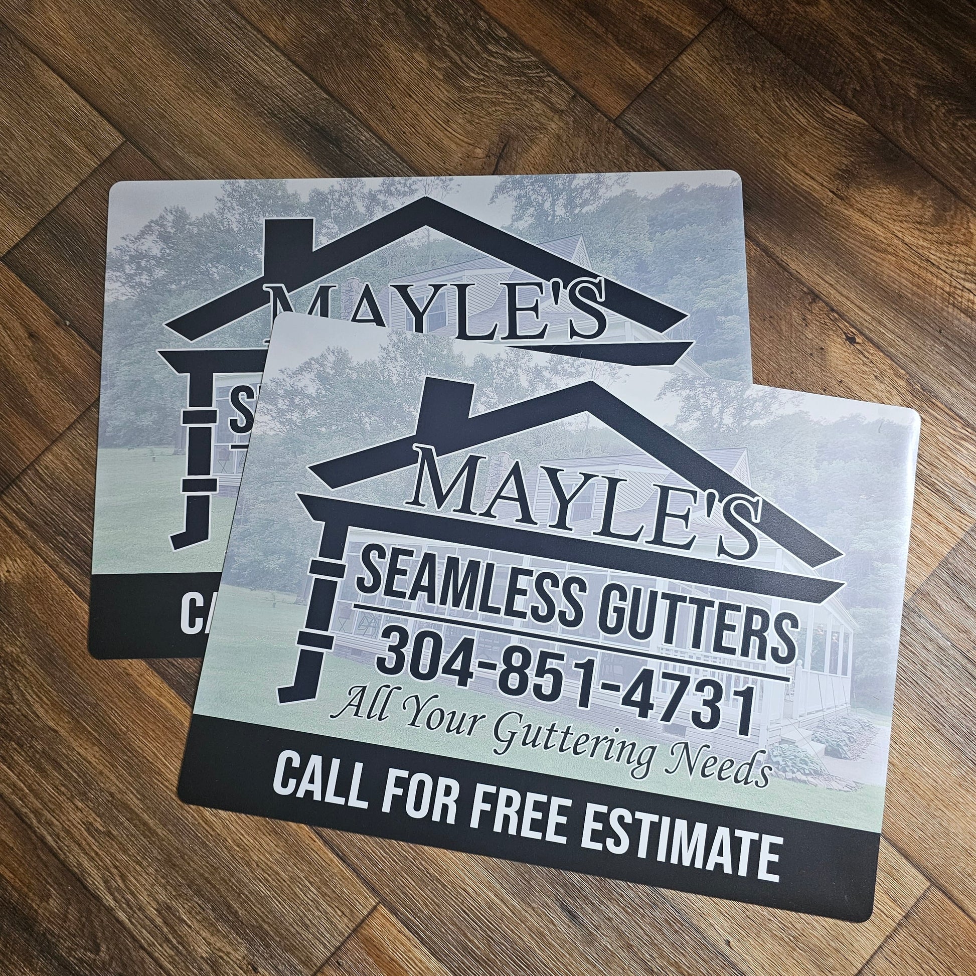 Mayle's Seamless Gutters promotional car magnet signs on a wooden background