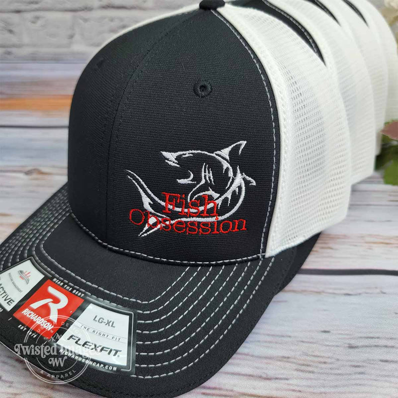 Custom embroidered Fish Obsession trucker hats featuring red and white shark logo on black and white Richardson Flexfit caps