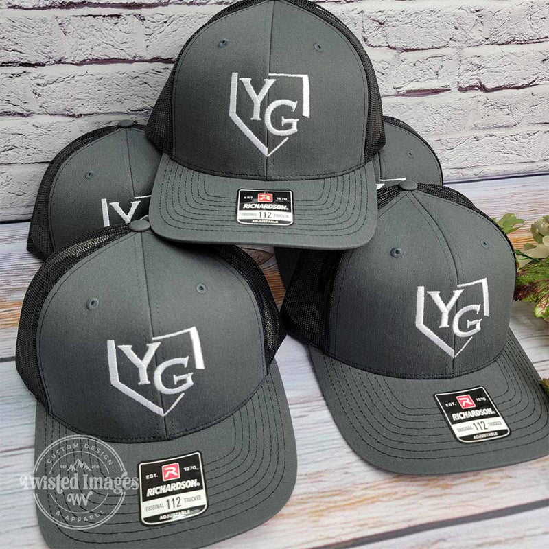 Stack of gray and black Richardson 112 trucker hats with Young Guns logo custom embroidered in white thread