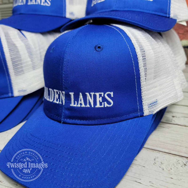 Blue and white mesh trucker hats with Golden Lanes text custom embroidered in white thread for local bowling alley staff