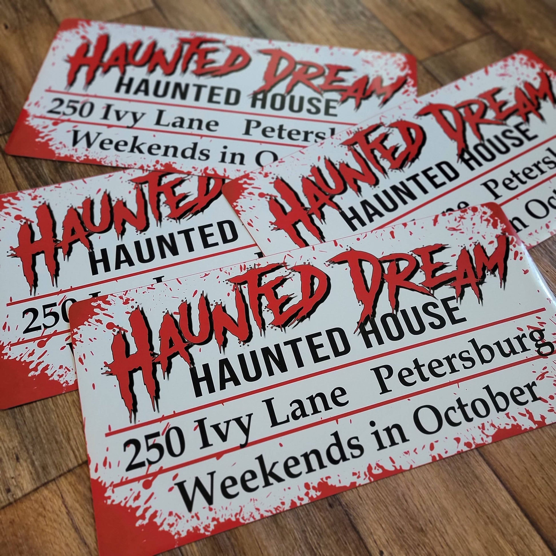 Magnetic car signs for haunted house with red and black text on a wooden surface.